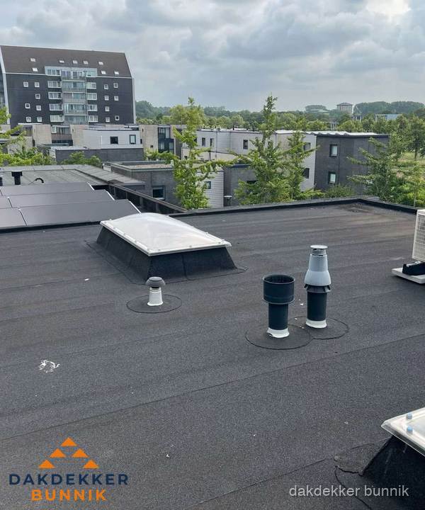 Groot plat dak met lichtkoepel en dakdoorvoeren in Bunnik