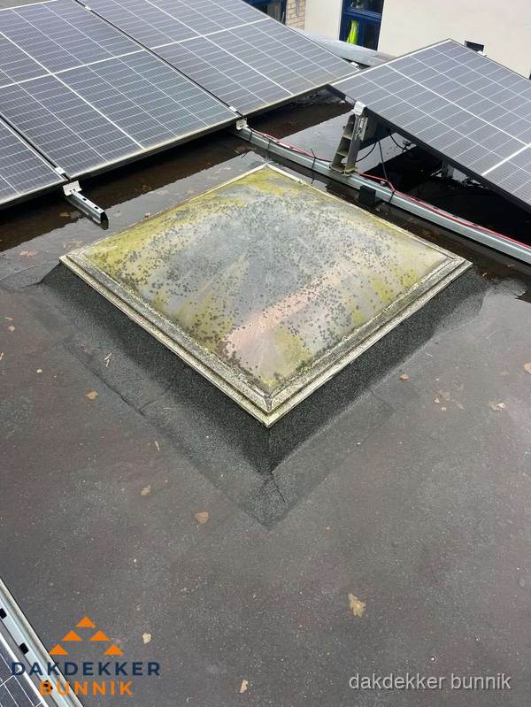 Vervuilde lichtkoepel op plat dak met zonnepanelen in Bunnik