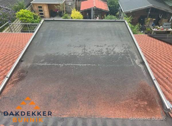 Verouderd plat dak met slijtage tussen schuine daken in Bunnik