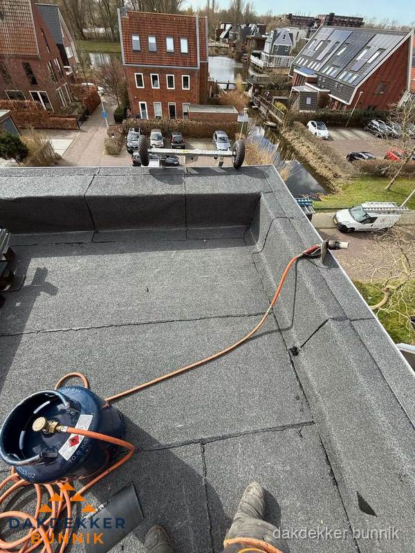 Dakdekker aan het werk met gasbrander op plat bitumen dak in Bunnik