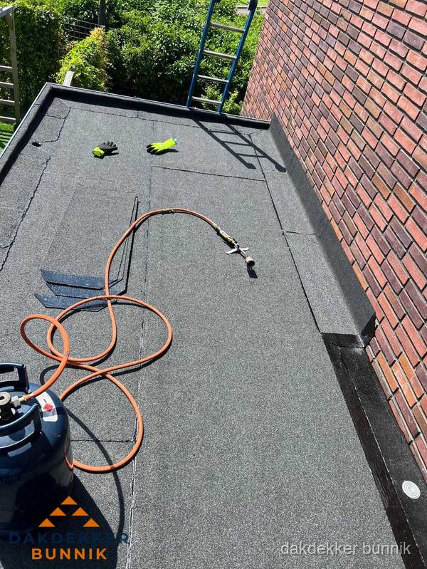 Plat dak met bitumen en brandgereedschap van dakdekkersbedrijf in Bunnik
