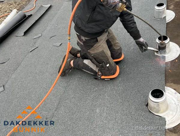 Dakdekker repareert bitumen dakleer bij dakdoorvoer in Bunnik