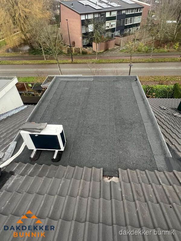 Plat dak inspectie met bitumen bedekking naast schuin pannendak in Bunnik