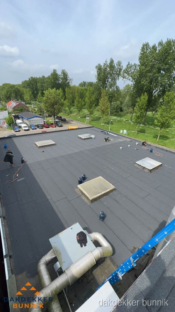Dakdekker aan het werk op groot plat dak met bitumen in Bunnik Dakdekker aan het werk op groot plat dak met bitumen in Bunnik