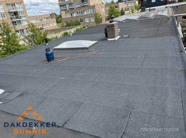 Bitumen dakbedekking op plat dak met lichtkoepel en schoorsteen in Bunnik